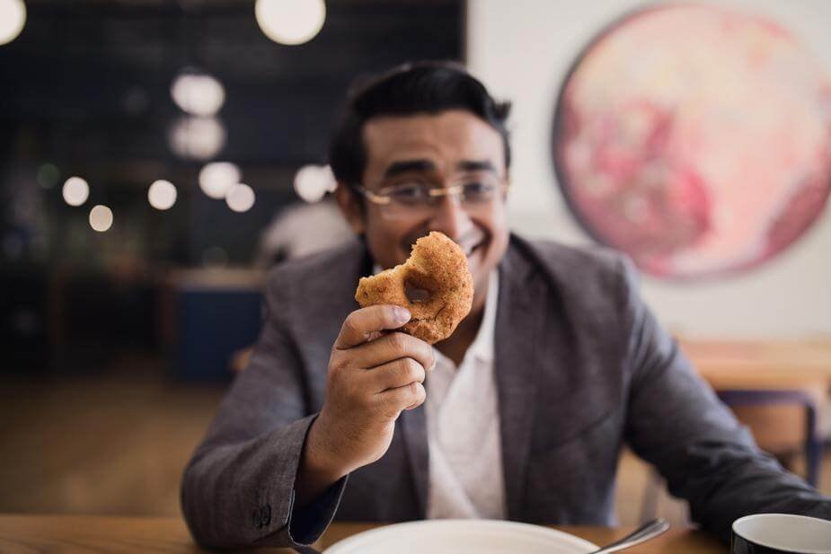 Man holding donut in cafe