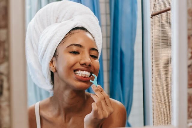 woman flossing in mirror